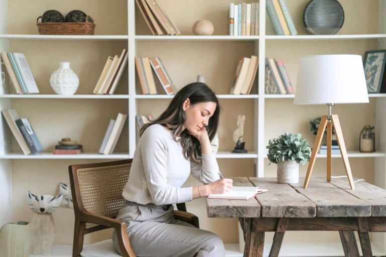 woman sitting at a desk writing in a journal