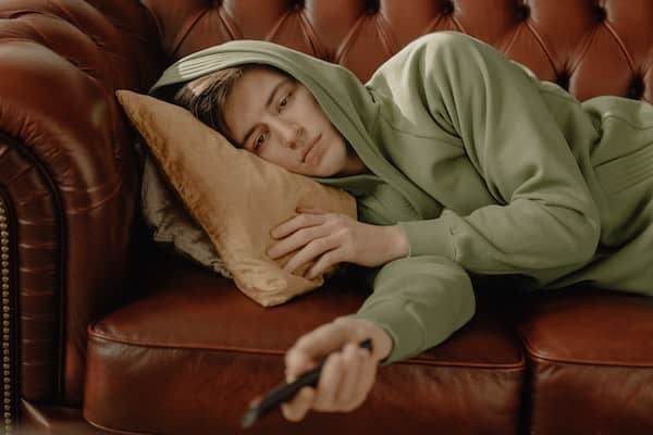 a man laying on the couch with remote in hand