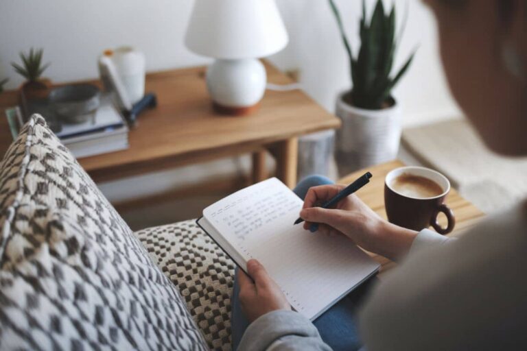 woman writing in a journal with a cup of coffee