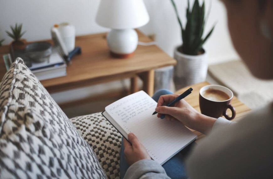 woman writing in a journal with a cup of coffee